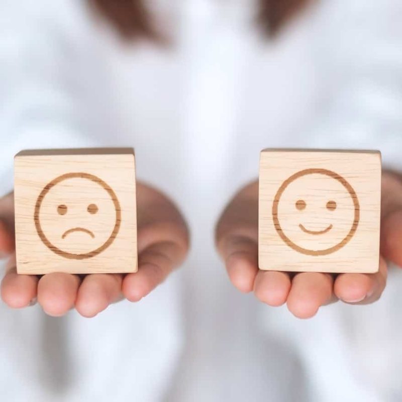 Woman holding smile and angry emotion face block. Customer choose Emoticon for user reviews